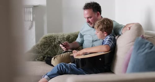 Padre e hijo viendo un vídeo tutorial sobre cómo tocar la guitarra