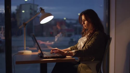Woman Working on Laptop Late at Night in Office