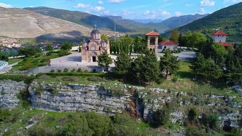 Panoramic drone shot of an Christian church with a small town Trebinje, Bosnia in the valley of a mo