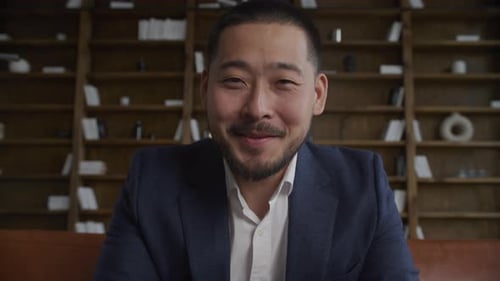 Cheerful Young Man Waving at Camera Indoors