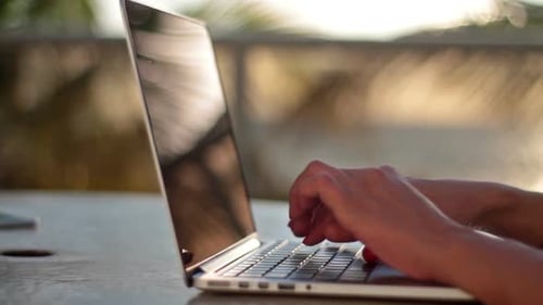 Girl Typing on a Laptop on the Beach at Sunrise Beach