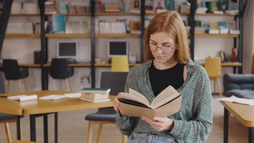 Young Woman Student Reading a Book in the Library or Classroom Interested Reading a Book Students in