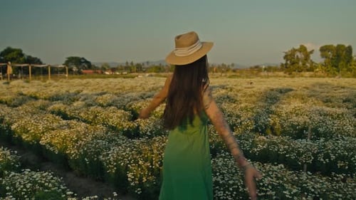 Junge Frau geht durch die Blumenwiese im dichten hohen Gras