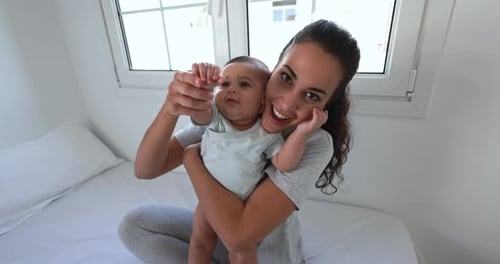 Happy Woman Holding Cute Baby in Bright Room