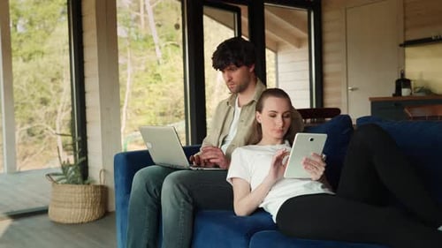 Couple relaxing at home using devices