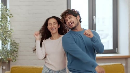 Happy young couple dancing indoors with energy