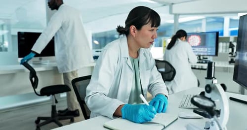 Scientist writes at desk in modern laboratory