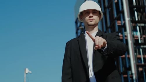 Engineer Pointing at the Camera by a Building