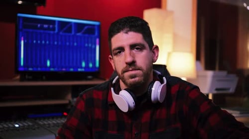 Close Up View of Serious Young Sound Engineer in a Professional Music Studio Wearing Headphones and