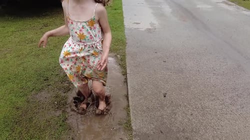 Girl Splashing Barefoot in Muddy Puddle
