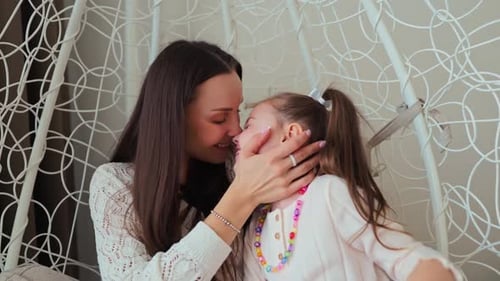 Loving Mother and Daughter Cuddling Indoors Together