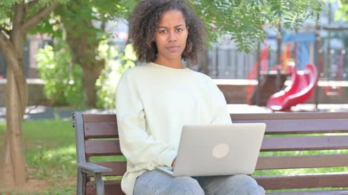 Woman Uses Laptop on Park Bench Outdoors