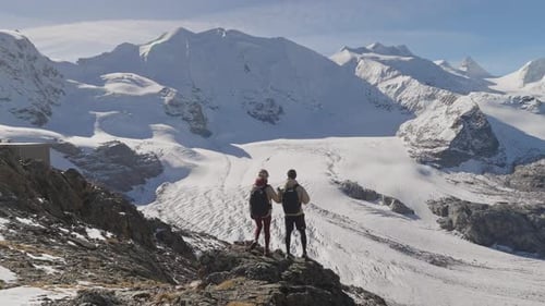 Adventure couple reaching viewpoint overlooking large glacier in Alps