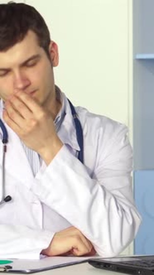 Exhausted Male Doctor Takes a Moment to Relieve Stress at the Office