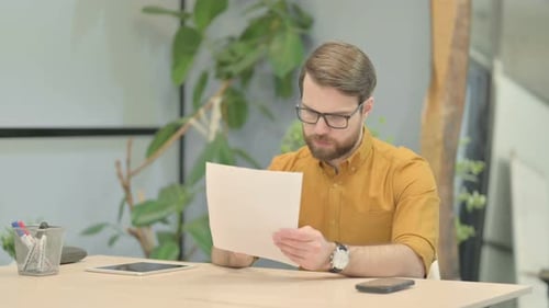 Young Man Reading Documents in Office