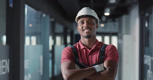 Smiling Construction Worker with Hardhat Stands in Office Hallway