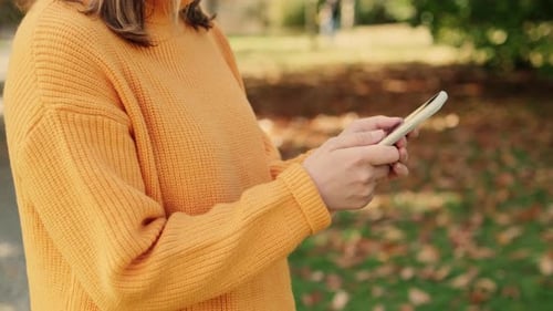 Woman Walks in Park Scrolling Through Social Media Feed