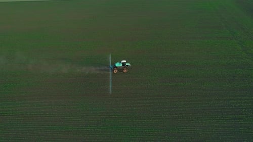 Tractor Sprays Crops in Rural Agricultural Field