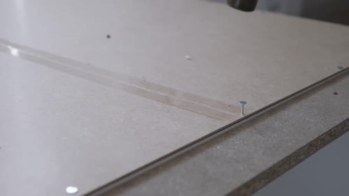 Slow motion close up of hammering a nail into the back of a wardrobe from Ikea.