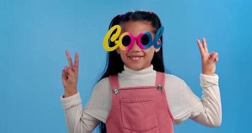 Peace sign, sunglasses and face of child in studio for confidence, trendy style