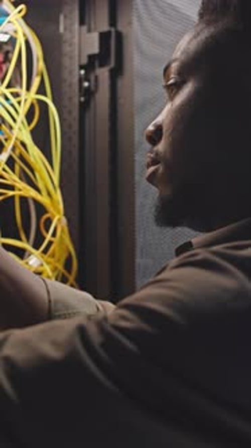 Man Working with Yellow Network Cables on Server