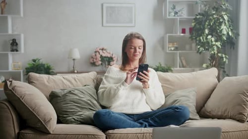 Woman Uses Phone on Couch in Living Room
