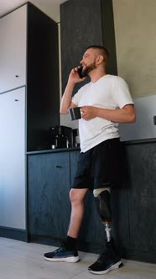 Positive Man with Prosthetic Leg Drinking Coffee and on Phone