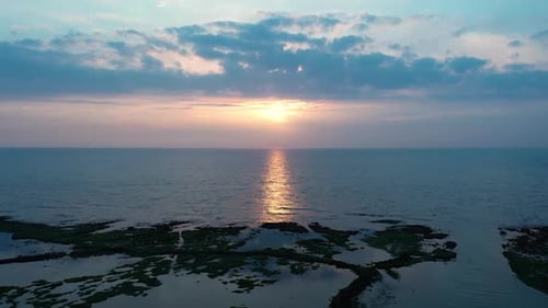 Aerial flight towards magnificent sunset with light reflection in tranquil Pacific Ocean at North Co