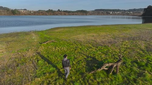 Aerial View Of A Man Walking Through The Meadows By The Lakeshore.