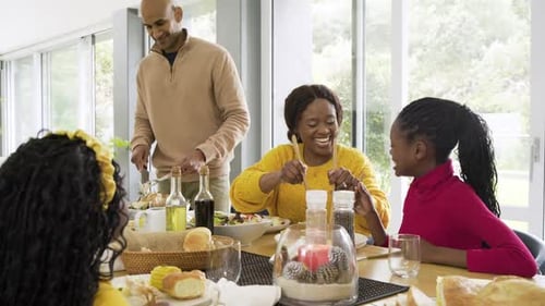 Extended family gathering around table sharing salad for dinner, triggered by father slicing meat