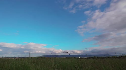 timelapse of clouds passing over a field with blue sky and mountains