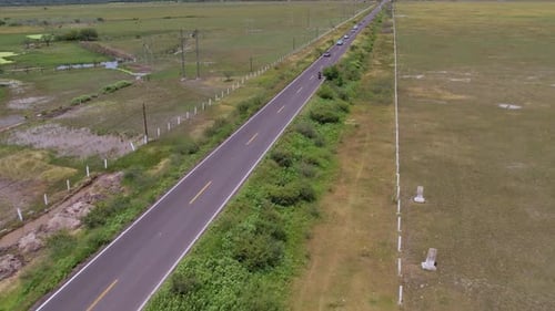 aerial shot of a motorcycle starting on a road and a green meadow on both sides