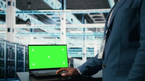 Green Screen Mockup Laptop Used By Engineer in Server Farm