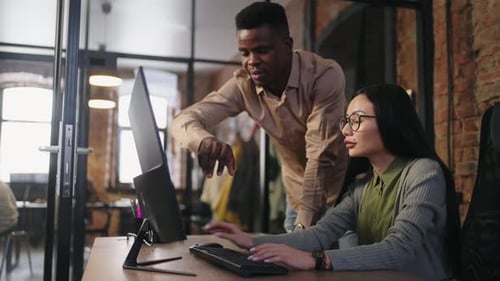 Pair of Multiethnic Colleagues In Office Discussing Design of Website Or Financial Reporting