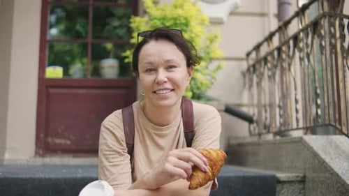 Woman Sits with Coffee and Croissant