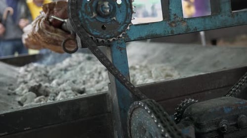 Hog roast spit turned by mechanical chain driven cogwheels machine, close up.