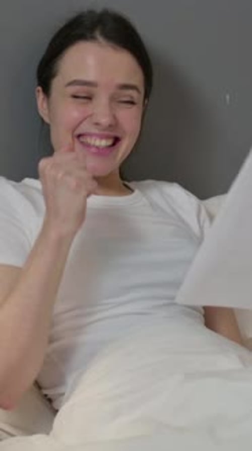 Excited Woman Reading Good News in Bed