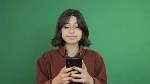 Woman Smiling and Thinking with Smartphone on Green