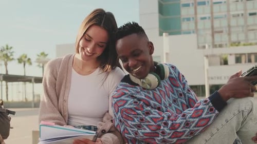 Student couple studying while sitting outside the university