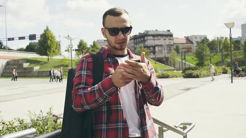Young Man Using Smartphone in Street