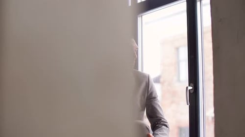 Man in Suit Talking on Phone by Window