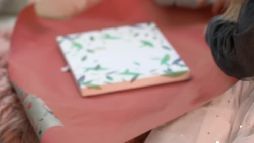 Close-up of little girl wrapping birthday presents or Christmas gift at home. Over Shoulder of femal