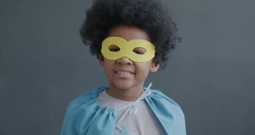 Slow Motion Portrait of Creative African American Kid in Superman Mask and Cape Smiling Looking at