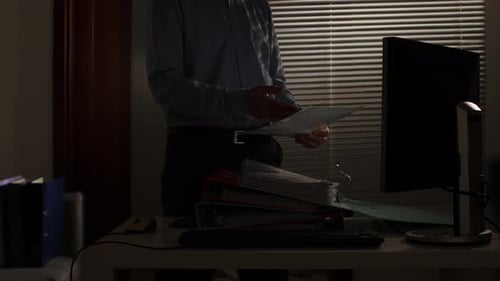 Man Reviews Documents at Desk Late at Night