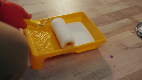 Paint Roller Being Covered in White Paint Indoors