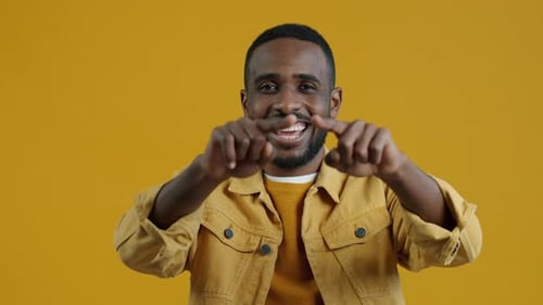 Smiling Man Points Directly at Camera on Yellow