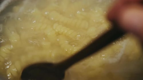 Pasta Boiling in Water Stirred With Wooden Spoon