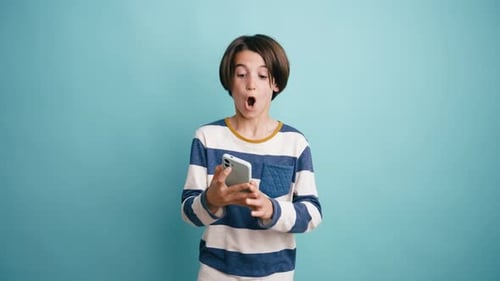 Excited Young Boy Celebrating a Victory on His Smartphone
