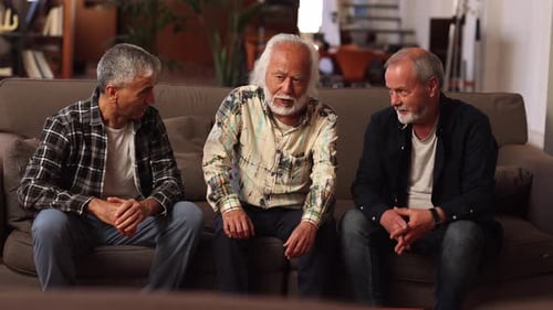 Three Mature Men Talking on Couch Indoors