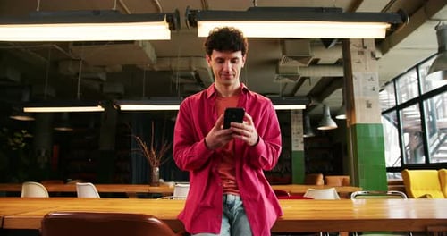 Man Smiling Using Smartphone in Relaxed Office Setting